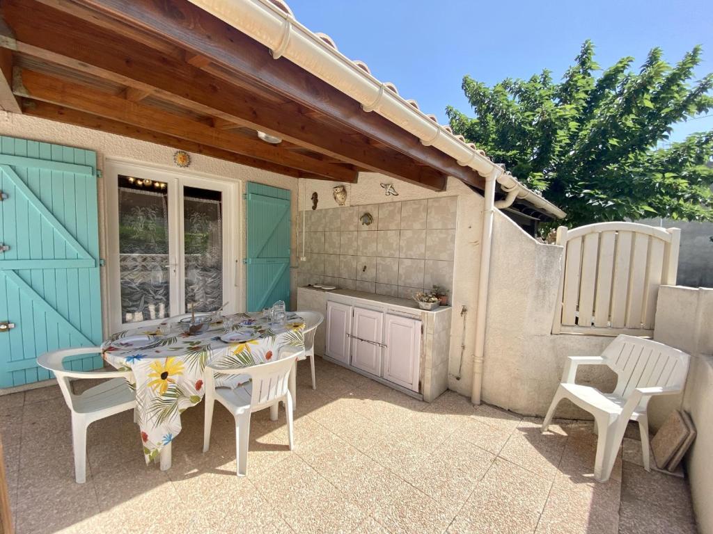 un patio avec une table et des chaises et une cuisine dans l'établissement Villa T2 Mezzanine - 36m² - Climatisée - Proche Plage - 6 Pers - Parking Privé - FR-1-795-29, à Fleury