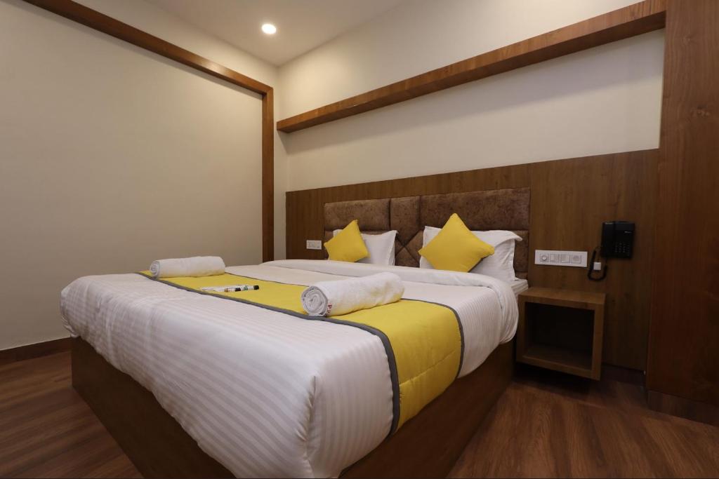 a bedroom with a large bed with yellow pillows at Hotel president park Coimbatore in Coimbatore