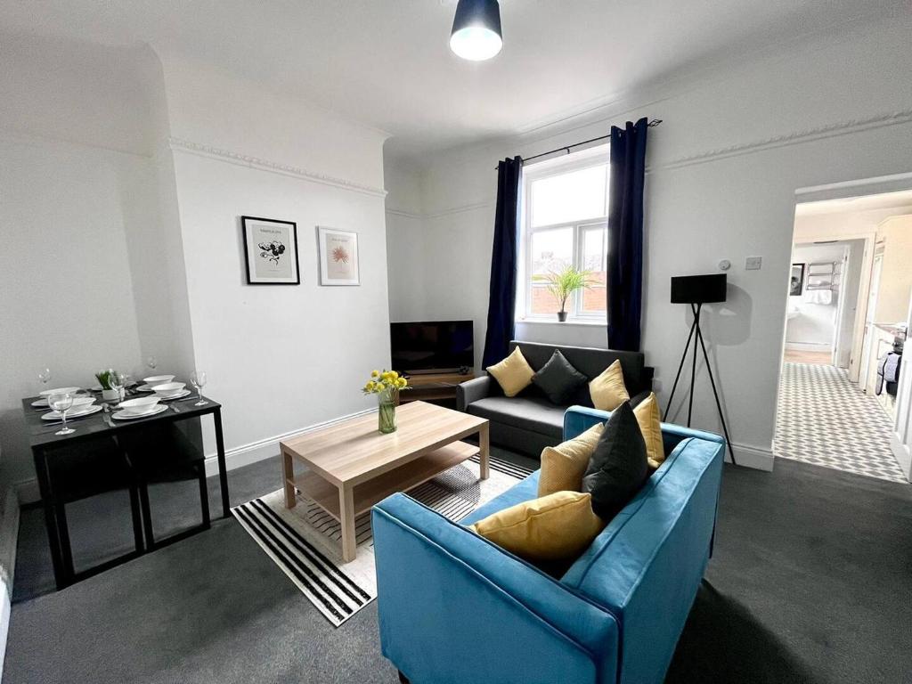 a living room with a blue couch and a table at Spacious 3 Bedroom House in Pallion