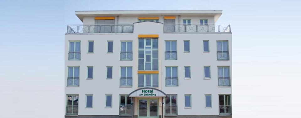 a white building with blue windows and a door at Hotel am Drömling in Versfelde