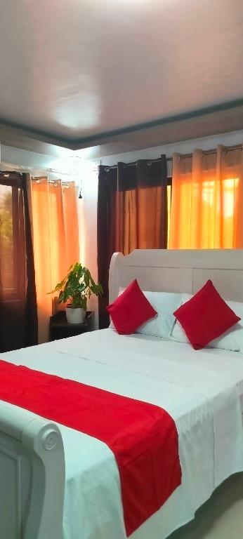 a bedroom with a large white bed with red pillows at Pacifico's Hostel in Barili
