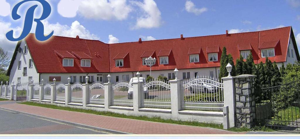 une clôture blanche devant un bâtiment avec un toit rouge dans l'établissement Rezydencja Nad Jeziorem Łebsko, à Łeba