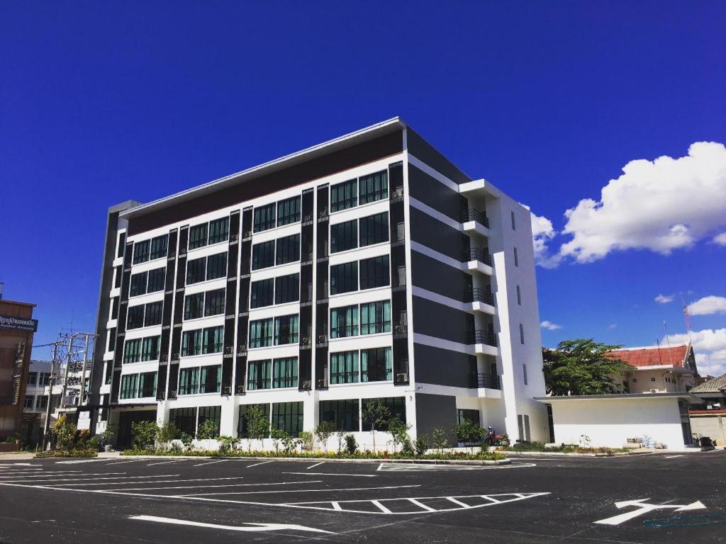 ein großes schwarzweißes Gebäude mit einem Parkplatz in der Unterkunft Sans Hotel in Ban Rong Chang