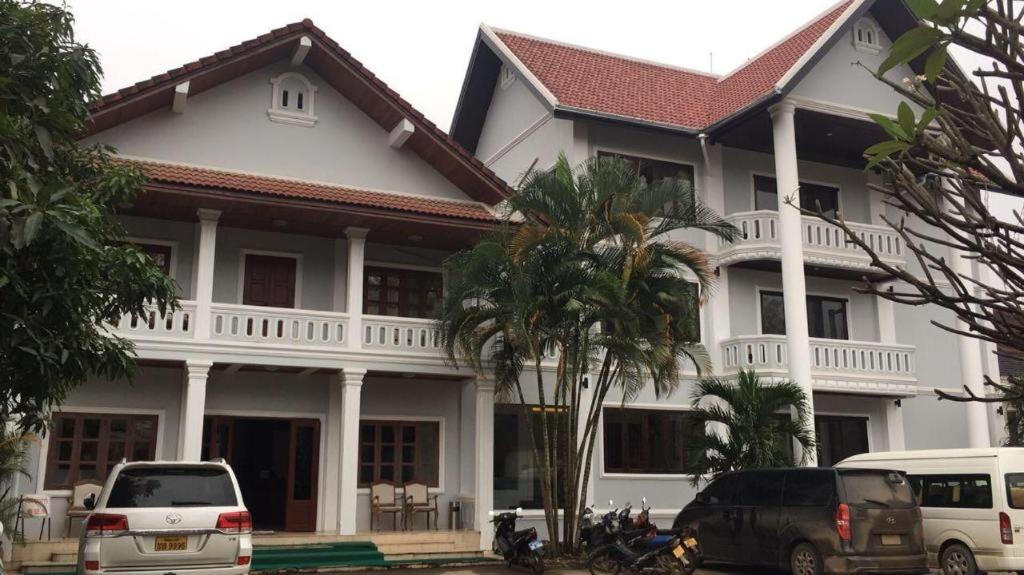 a white house with cars parked in front of it at Saysamphanh Hotel in Ban Nongkham