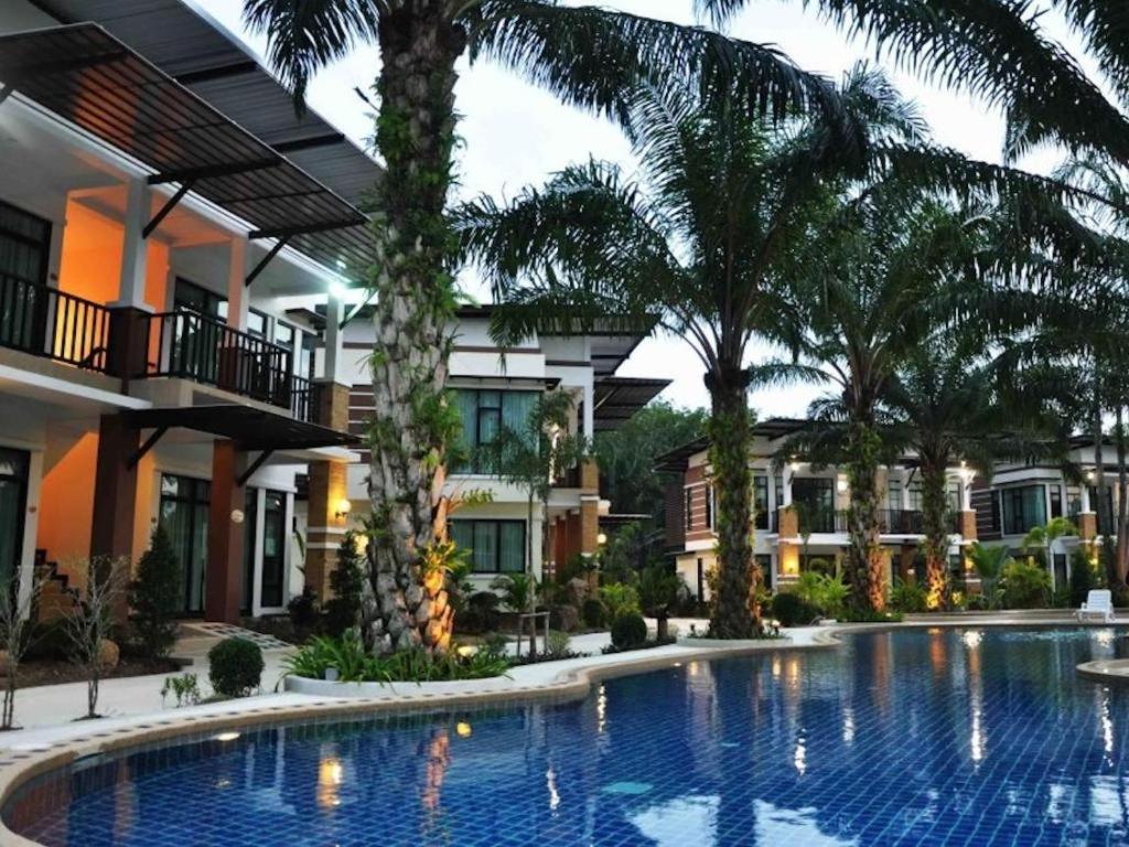 a swimming pool in front of a building with palm trees at Nattha Waree Hot Spring Resort and Spa in Ao Nang Beach