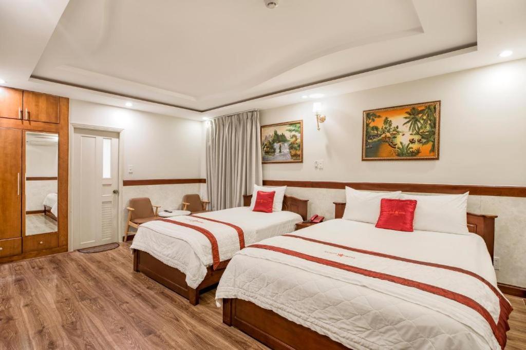 a hotel room with two beds with red pillows at Ha Oanh Hotel in Ho Chi Minh City