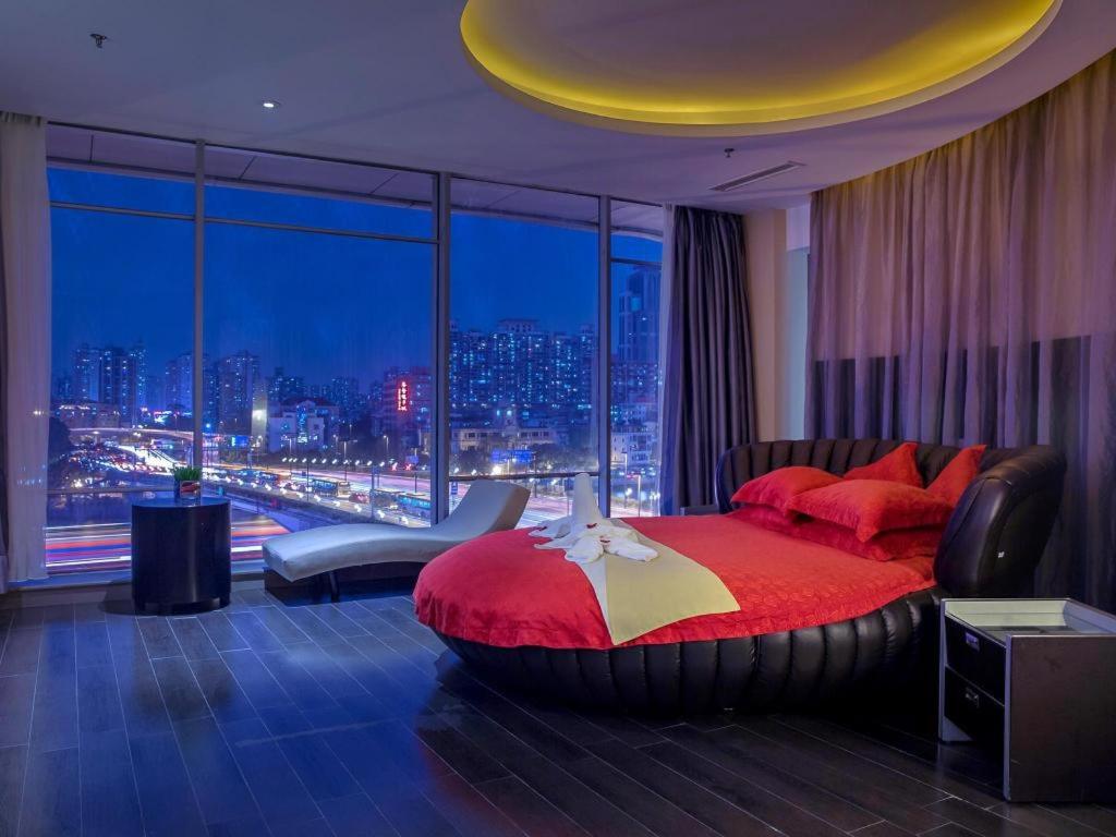a bedroom with a red bed and a large window at Guangdong Nanmei Osotto Hotel in Guangzhou