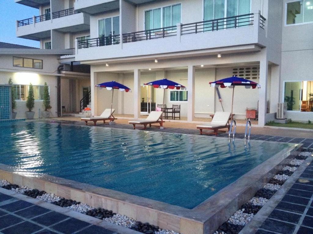 una piscina con sedie e ombrelloni di fronte a un edificio di Sea Mountain Khanom Hotel a Ban Phang Phrao