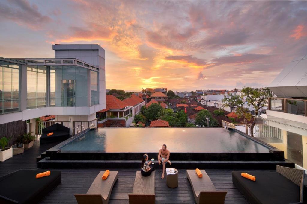 a man and a woman sitting on the edge of a swimming pool at Fashion Hotel Legian in Legian