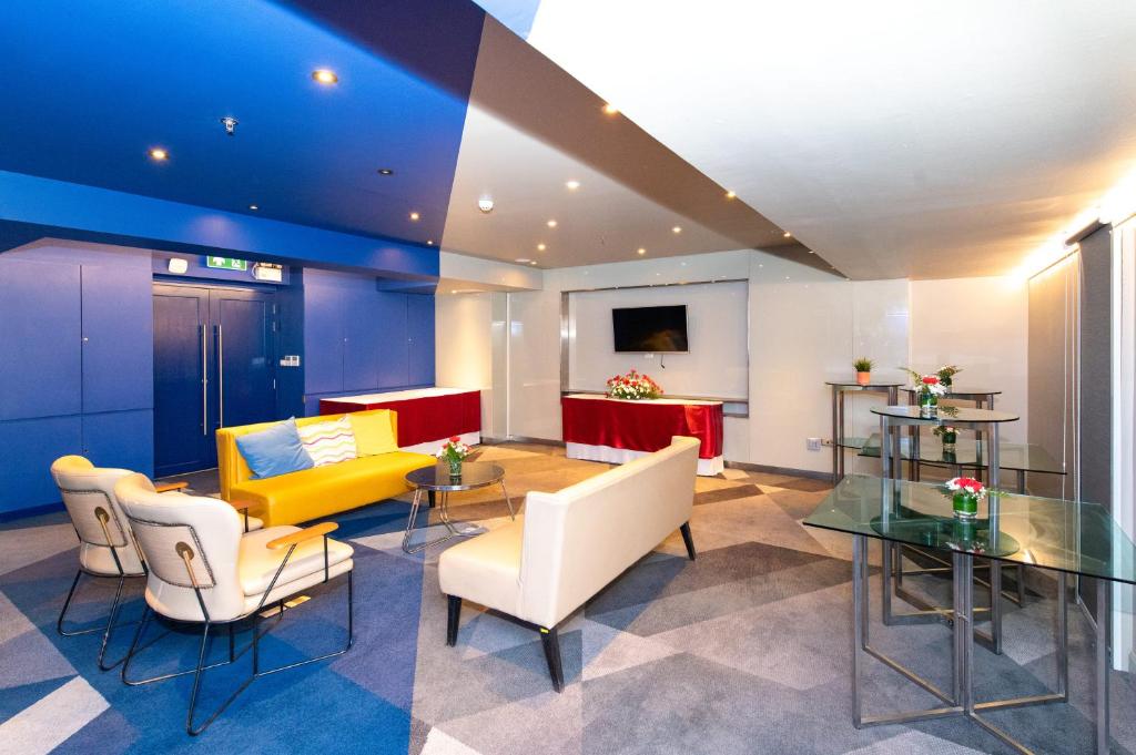 A colourful hotel lounge with a yellow sofa, armchairs and informal seating.
