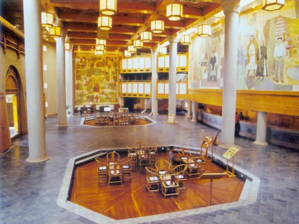 a large room with tables and chairs in a building at The Silk Road Dunhuang Hotel in Dunhuang