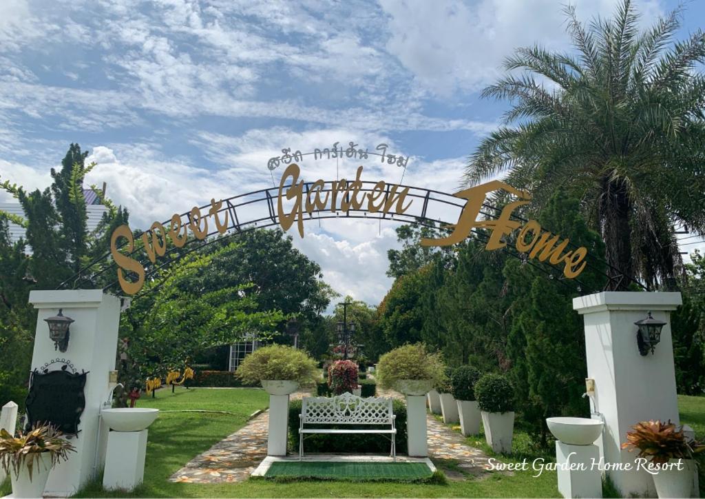 une porte vers un jardin avec un banc sous un panneau dans l'établissement Sweet Garden Home Resort, à Ban Nan Ya