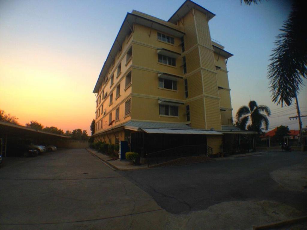 a tall yellow building with a sunset in the background at Seksub Place in Phra Nakhon Si Ayutthaya