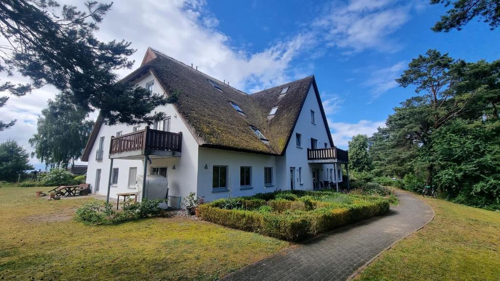 a large white house with a gambrel roof at Fewo 2 Stueven im Reetdachhaus Fewo cc in Kolpinsee