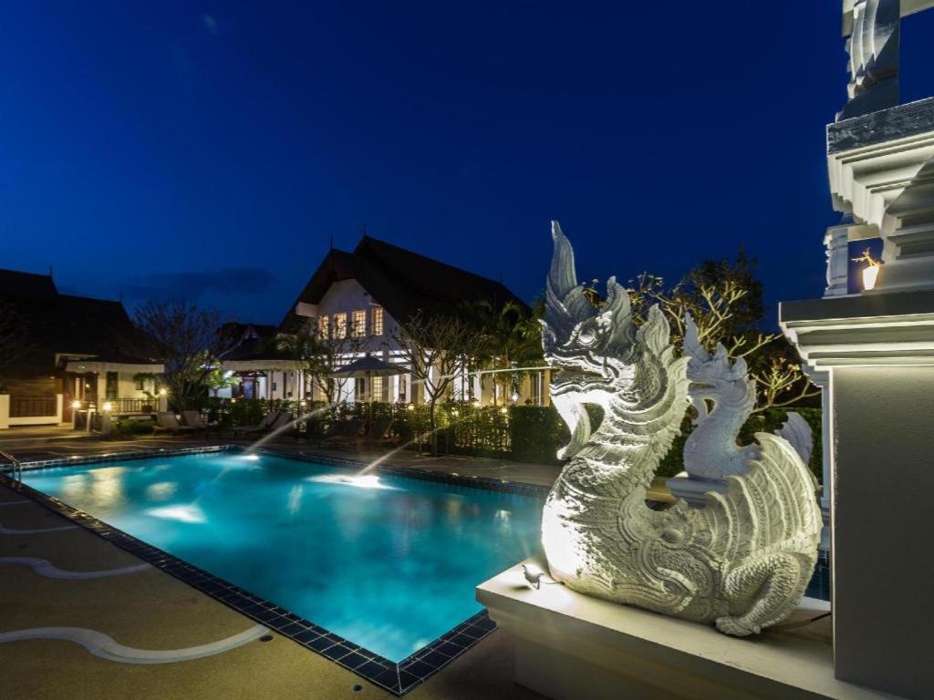 a statue of a dragon sitting next to a swimming pool at Doltara Boutique Resort in Chiang Mai