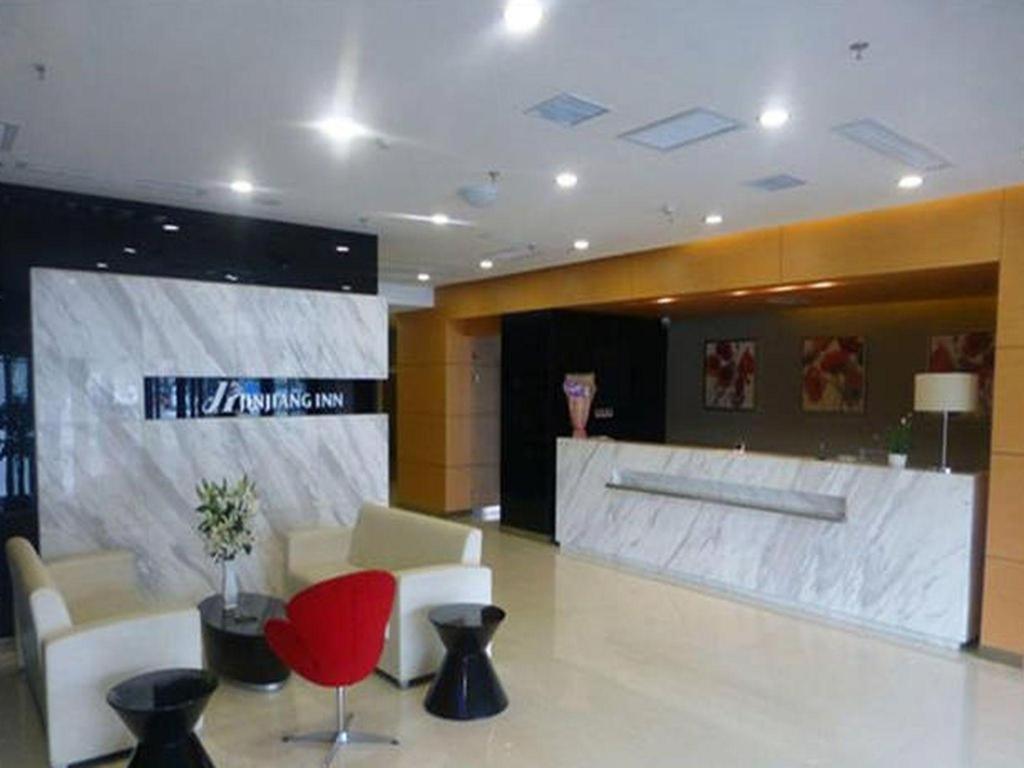 a lobby with a reception desk and red chairs at Jinjiang Inn Changchun Hongqi Street in Changchun