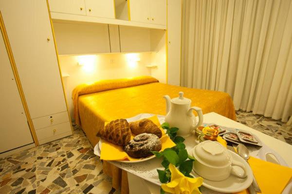 ein Zimmer mit einem Bett und einem Tisch mit Essen darauf in der Unterkunft Hotel Medusa in Sottomarina