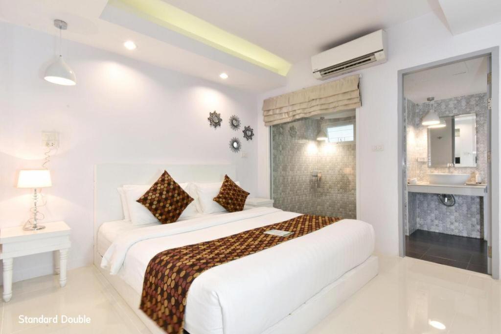 a white bedroom with two beds and a window at NanNakara Boutique Hotel in Nan