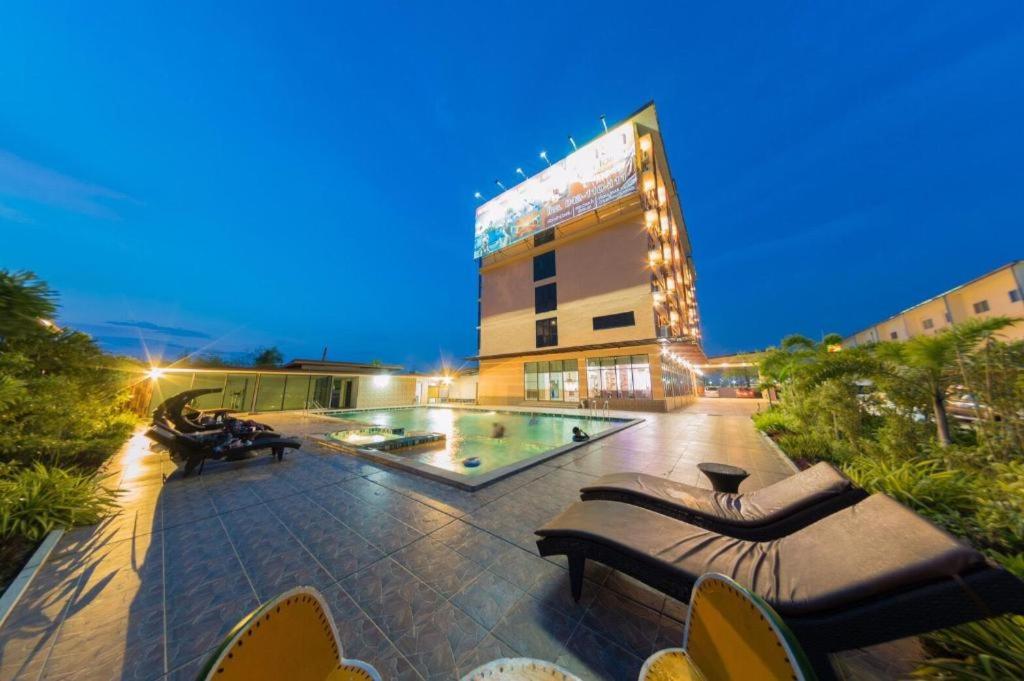 een groot gebouw met een zwembad 's nachts bij phatra boutique hotel in Udon Thani