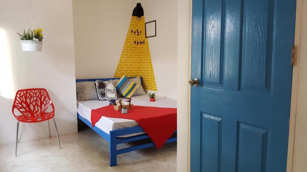 a room with a bed and a table with a building on the wall at The Sugar Hostel in Nonthaburi