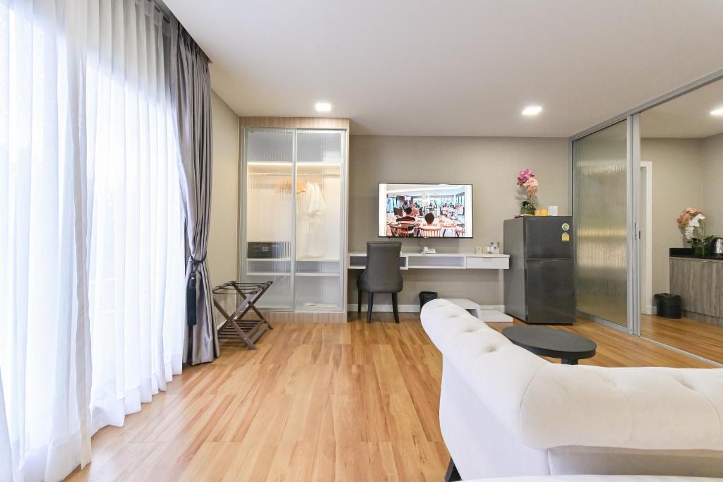 A living area with a desk, television, mini-fridge and glass-front storage.