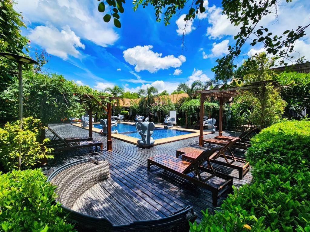 a swimming pool with wooden benches and a swimming poolvisor at Baan Kiangnam Pattaya Resort in Ban Pong
