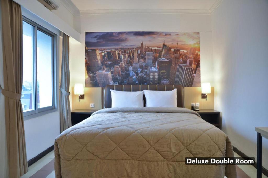 Un dormitorio con una cama con un cuadro en la pared. en Sleepzzz Hotel Senayan, en Yakarta
