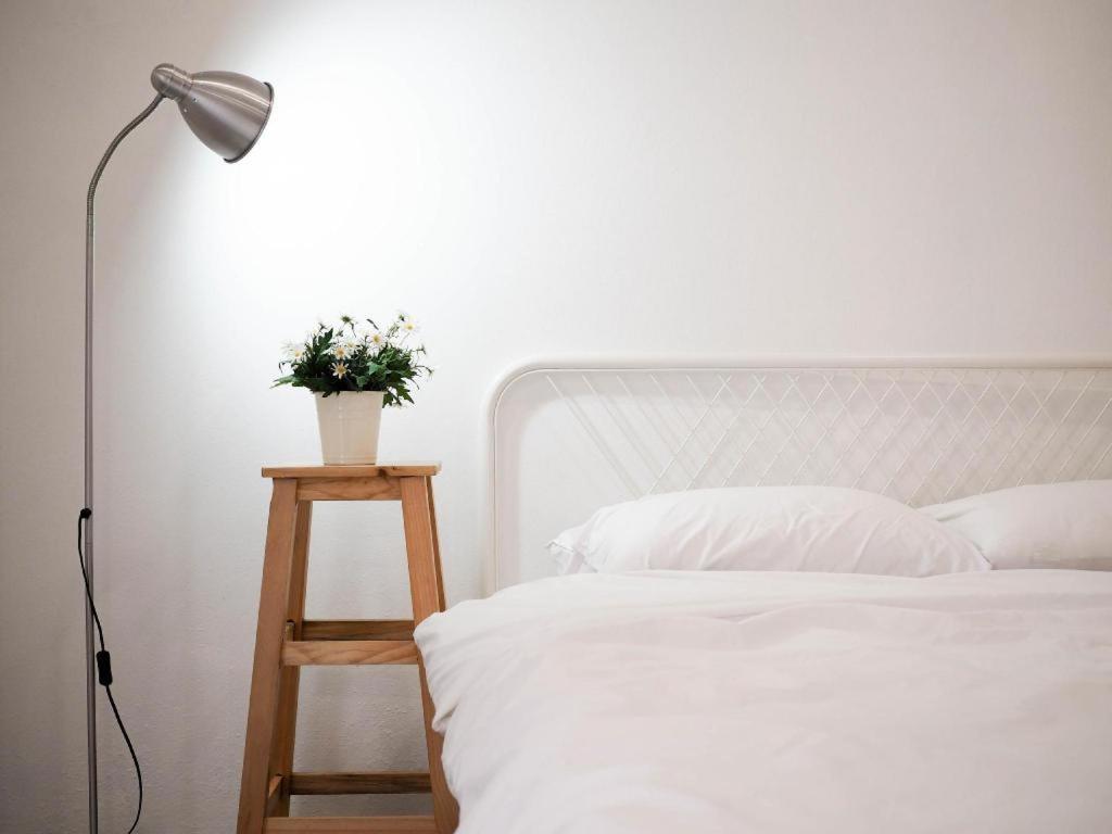 a white bed with a lamp and a plant on a table at Unyak Room Ayutthaya in Phra Nakhon Si Ayutthaya