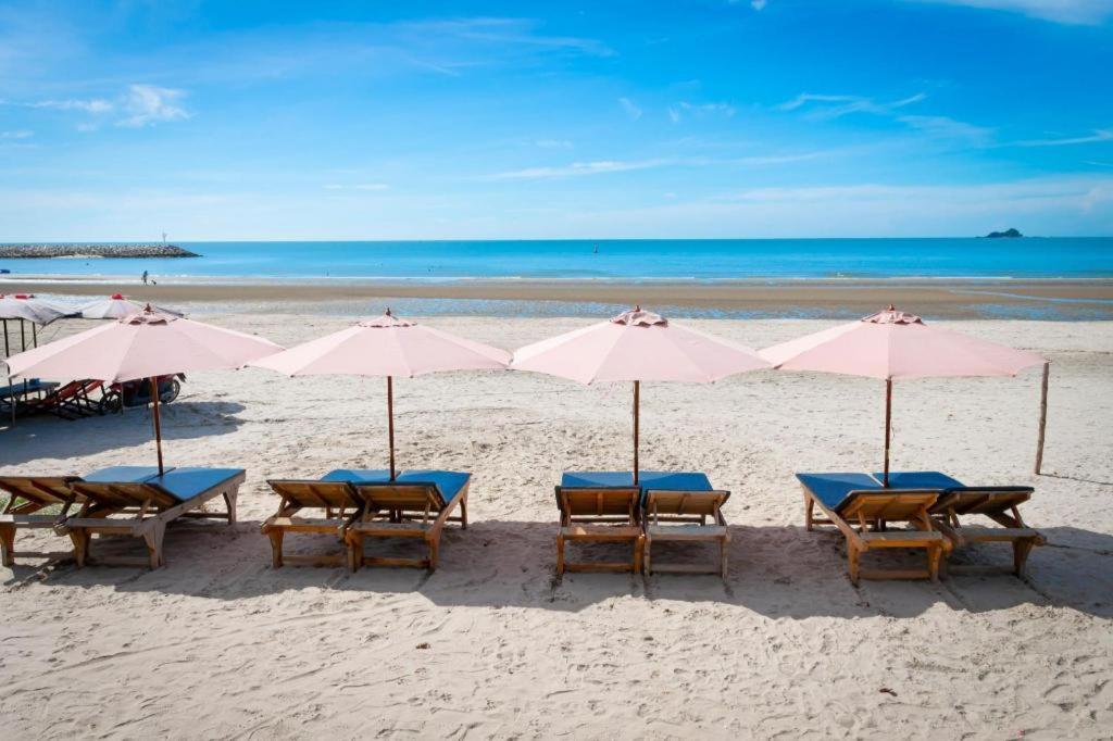 a group of tables and umbrellas on a beach at Blue Wave Hotel Hua Hin in Hua Hin