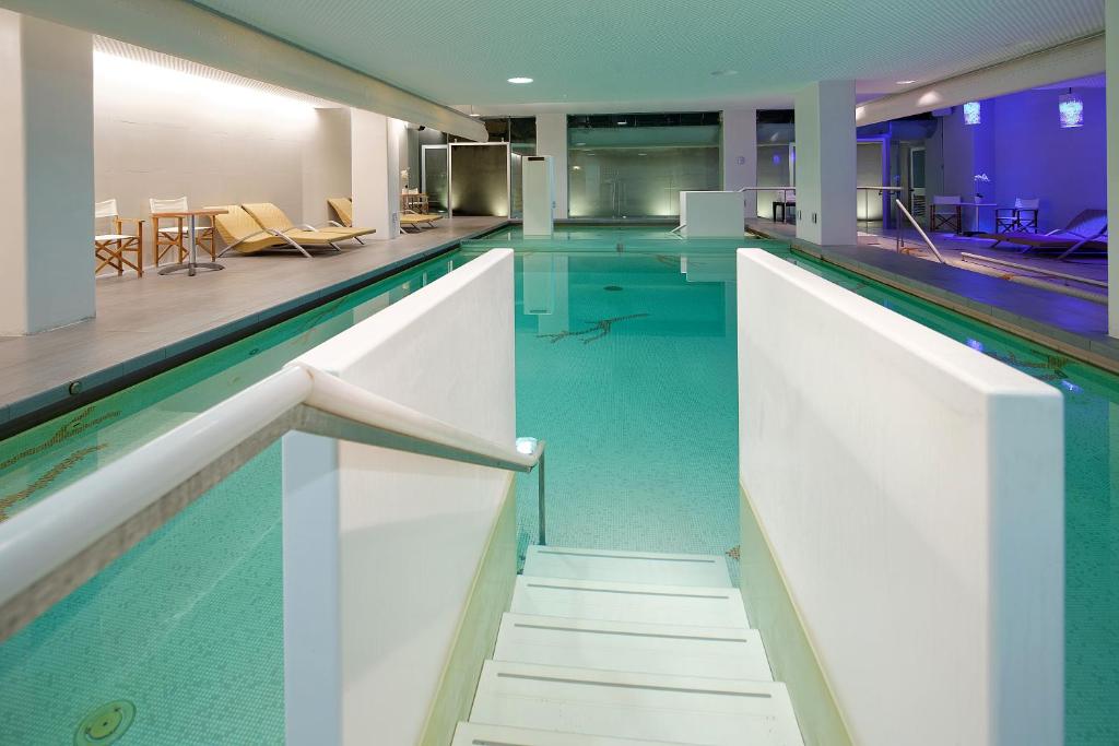 an indoor swimming pool with blue water in a building at Hotel Parco Smeraldo Terme in Ischia