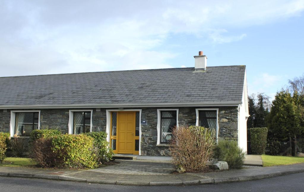 a house with a yellow door on a street at Riverlodge Self Catering in Kenmare