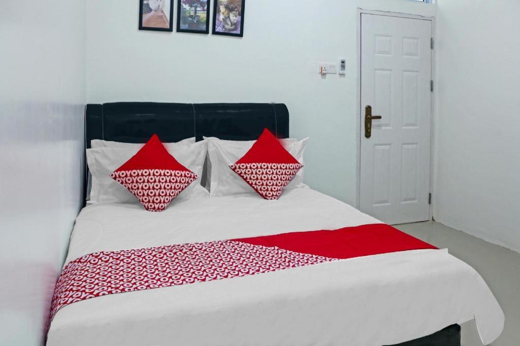 OYO 90609 Mimi & Coco Homestay في Pulau Sembakau Kecil: سرير عليه وسائد حمراء وبيضاء