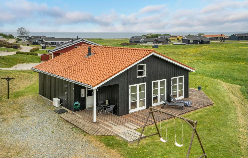 una casa nera con un tetto arancione e un'altalena di Holiday Home Vinkelbæk Ix a Nordborg