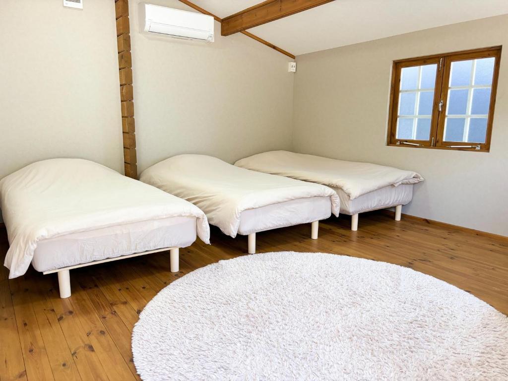 three beds in a room with a white rug at the room - Vacation STAY 39639v in Kannoura