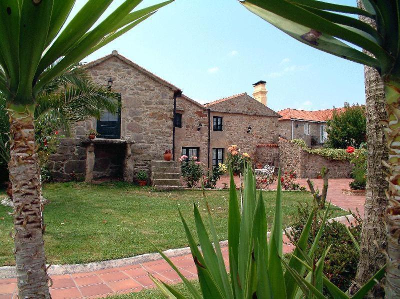 a large stone house with a palm tree in front of it at Os Migueliños in Catoira
