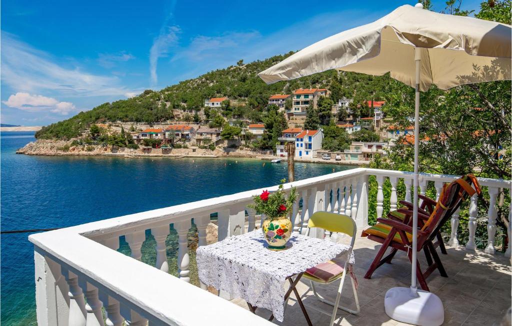 a balcony with a table and an umbrella and the ocean at Stunning Apartment In Senj With Kitchen in Starigrad