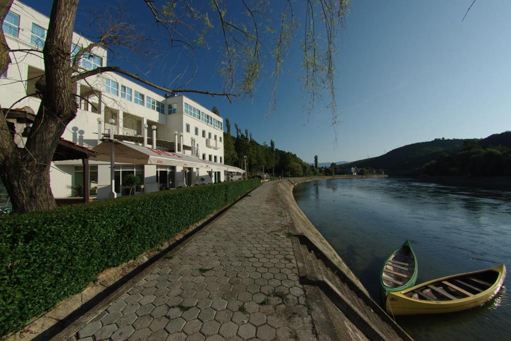 Hotel Sv. Mihovil في Trilj: نهر به زورقين متوقفين بجانب مبنى