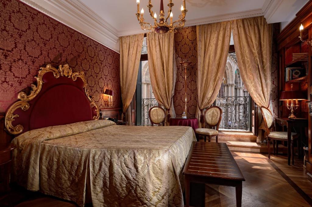 a bedroom with a large bed and a chandelier at Bellevue Luxury Rooms - San Marco Luxury in Venice