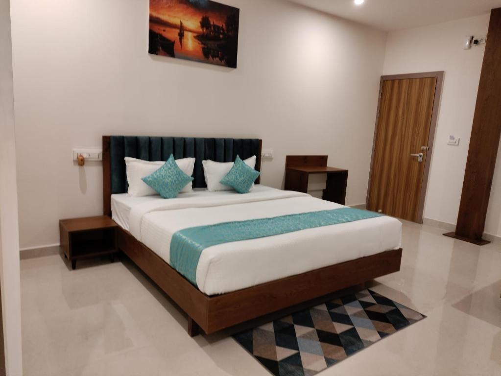 a bedroom with a large bed with blue pillows at Zing Rooms by GuestHouse Suites in Bengaluru