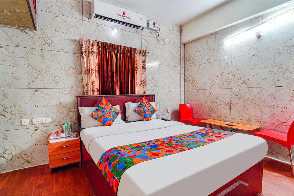 a bedroom with a bed and a red chair at FabExpress Apple Grand Gandhipuram in Coimbatore