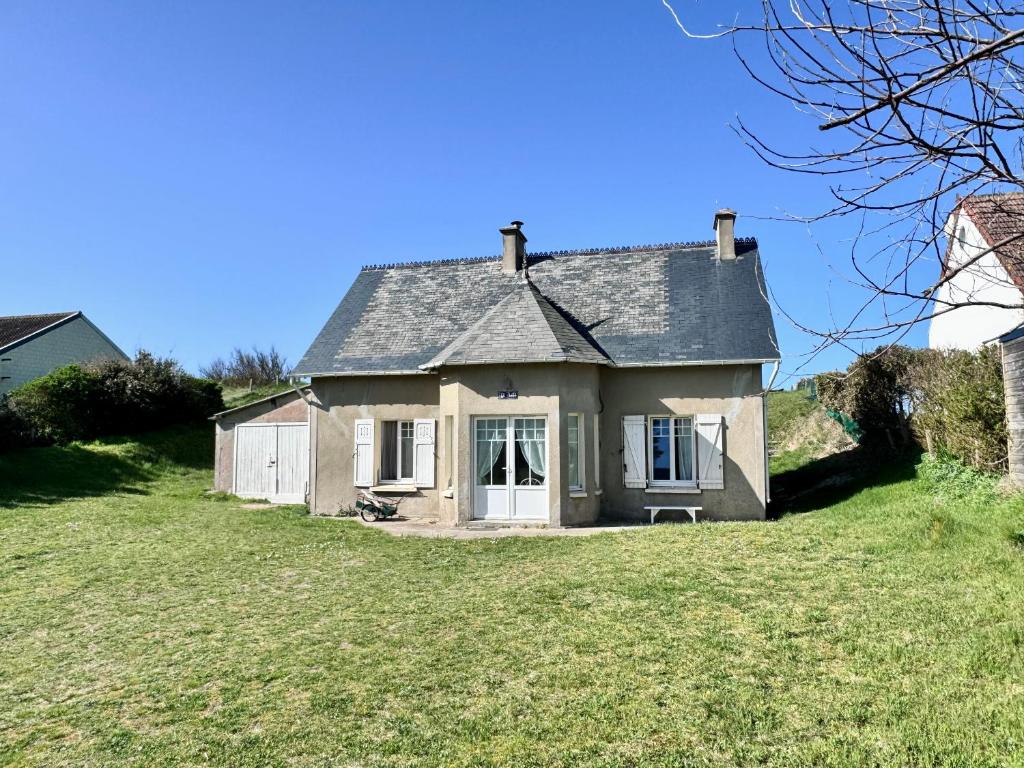une petite maison sur une colline avec une cour herbeuse dans l'établissement Maison les Flots dot Fr, à Denneville