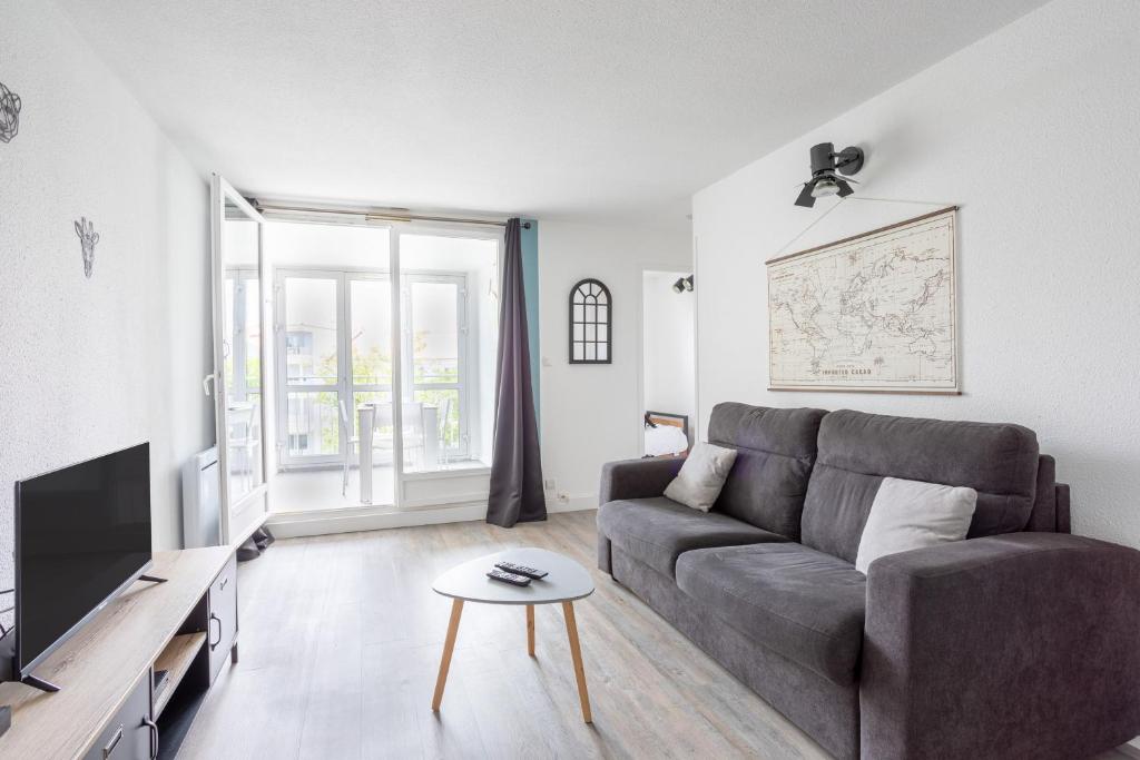 un salon avec un canapé et une télévision dans l'établissement Le Mercure, à Les Sables-dʼOlonne