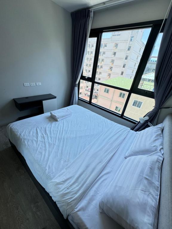 a bed in a room with a large window at 芭提雅市中心The Base 高端公寓酒店 in Pattaya