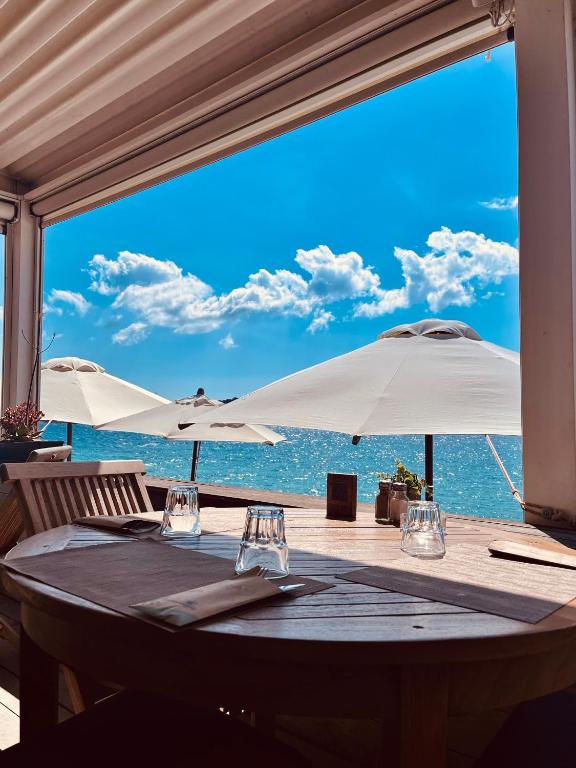 une table avec deux parasols blancs et l'océan dans l'établissement Résidence Domaine De Caranella, à Porto-Vecchio