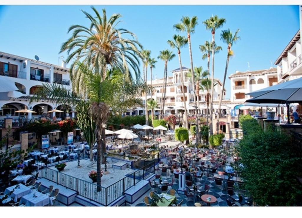 a resort with a lot of tables and chairs and palm trees at Casa Rox in Villamartin