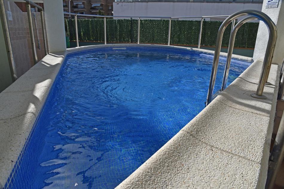 a large blue swimming pool with a metal railing at Apartamentos AR Dosjoimi in Lloret de Mar