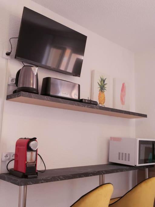 une étagère avec une télévision et un micro-ondes et deux chaises dans l'établissement Appartement - Saint-Cyprien, à Saint-Cyprien