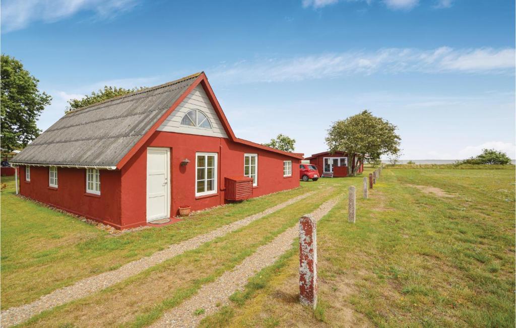 un granero rojo en un campo con una valla en One-Bedroom Holiday Home Rømø With Sea View 01, en Bolilmark