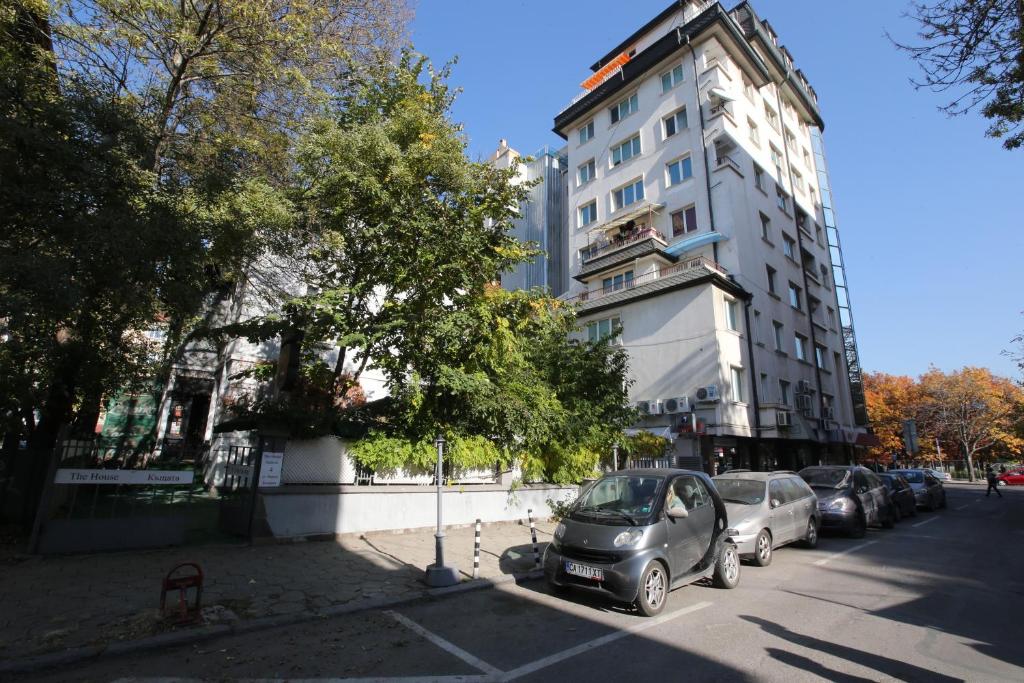 a group of cars parked next to a tall building at Hotel & Restaurant The House in Sofia