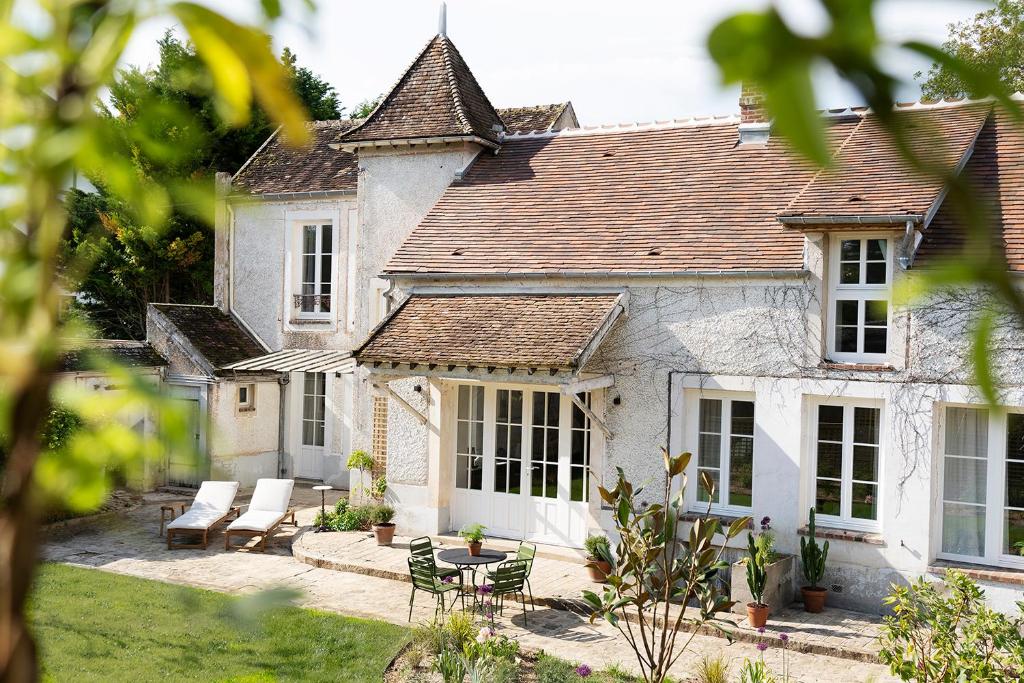 une grande maison blanche avec une table et des chaises dans l'établissement Maison dans un village de charme au coeur de la forêt de Fontainebleau, à Recloses